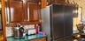 Dark wood cabinetry with exposed brass-tone hinges, green stone-finish countertop, and stainless steel French-door refrigerator