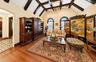 Vaulted ceilings featuring dark exposed beams, built-in wooden cabinetry, arched windows, and wood-finish flooring with inlay borders