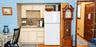 Kitchenette featuring custom cabinetry, stone countertops, dual-basin sink, and overhead wine rack storage