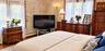 Interior room featuring hardwood flooring, patterned wallcovering, multi-pane windows, and wall-mounted light fixtures