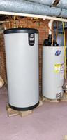 Mechanical system featuring an indirect-fired water heating tank and a separate vertical water heater with copper piping against a brick foundation wa