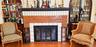 Fireplace featuring decorative dual-tone tile surround, recessed arched display cabinetry, and built-in wood shelving