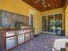 Outdoor kitchen with propane grill and seating area overlooking the pool. Easy access to the kitchen.