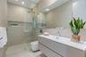 Modern bathroom featuring a textured floating vanity, integrated rectangular sink, wall-to-wall mirror, glass-enclosed walk-in shower with a rain-styl