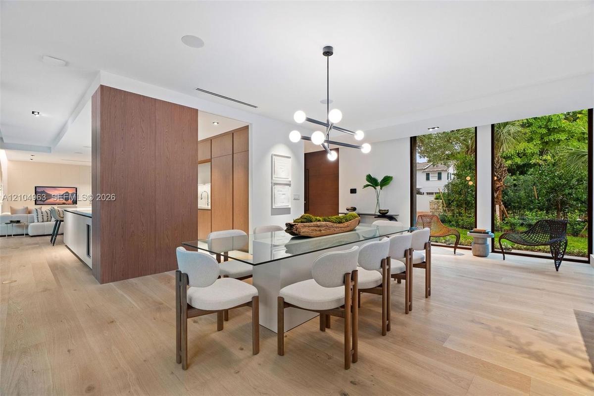Dining area featuring wood-finish flooring, floor-to-ceiling windows, a modern multi-light spherical chandelier, and floor-to-ceiling wood-panel accen
