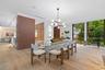 Dining area featuring wood-finish flooring, floor-to-ceiling windows, a modern multi-light spherical chandelier, and floor-to-ceiling wood-panel accen