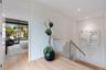 Wood-finish flooring, glass panel stair railing with a natural wood handrail, recessed ceiling lighting, and floor-to-ceiling sliding glass doors