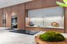 Modern kitchen featuring floor-to-ceiling wood-finish cabinetry, a large stone-surface island with an integrated induction cooktop, light-toned stone 