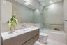 Floating vanity featuring a ribbed textured finish, integrated white basin, wall-to-wall mirror, glass-enclosed shower and tub combination, and full-h