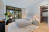 Floor-to-ceiling sliding glass door, custom walk-in closet with built-in shelving, wood-finish flooring, and recessed ceiling lighting