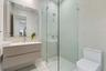 Floating vanity with integrated sink, walk-in shower featuring frameless glass enclosure, polished chrome hardware, and large-format wall tiling