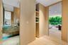 Custom light-toned wood cabinetry with integrated shelving, stone vanity with a rectangular sink, full-height wall mirrors, and wood-finish flooring