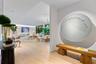 Open-concept interior featuring light wood-finish flooring, recessed ceiling lighting, wall-mounted accent lighting, and expansive floor-to-ceiling gl