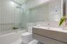 Floating vanity with ribbed cabinetry and integrated sink, frameless glass shower enclosure, rainfall showerhead, large wall-spanning mirror, and neut