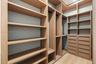 Custom walk-in closet featuring built-in wood-finish shelving, integrated hanging rods, and multi-drawer cabinetry with wood-finish flooring
