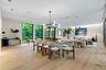 Open-concept living space featuring wood-finish flooring, floor-to-ceiling windows, recessed lighting, and a modern tiered geometric chandelier