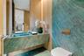 Floating vanity with integrated basin, teal stone wall cladding, floor-to-ceiling wood paneling, wall-mounted metallic flush actuator, and recessed ce