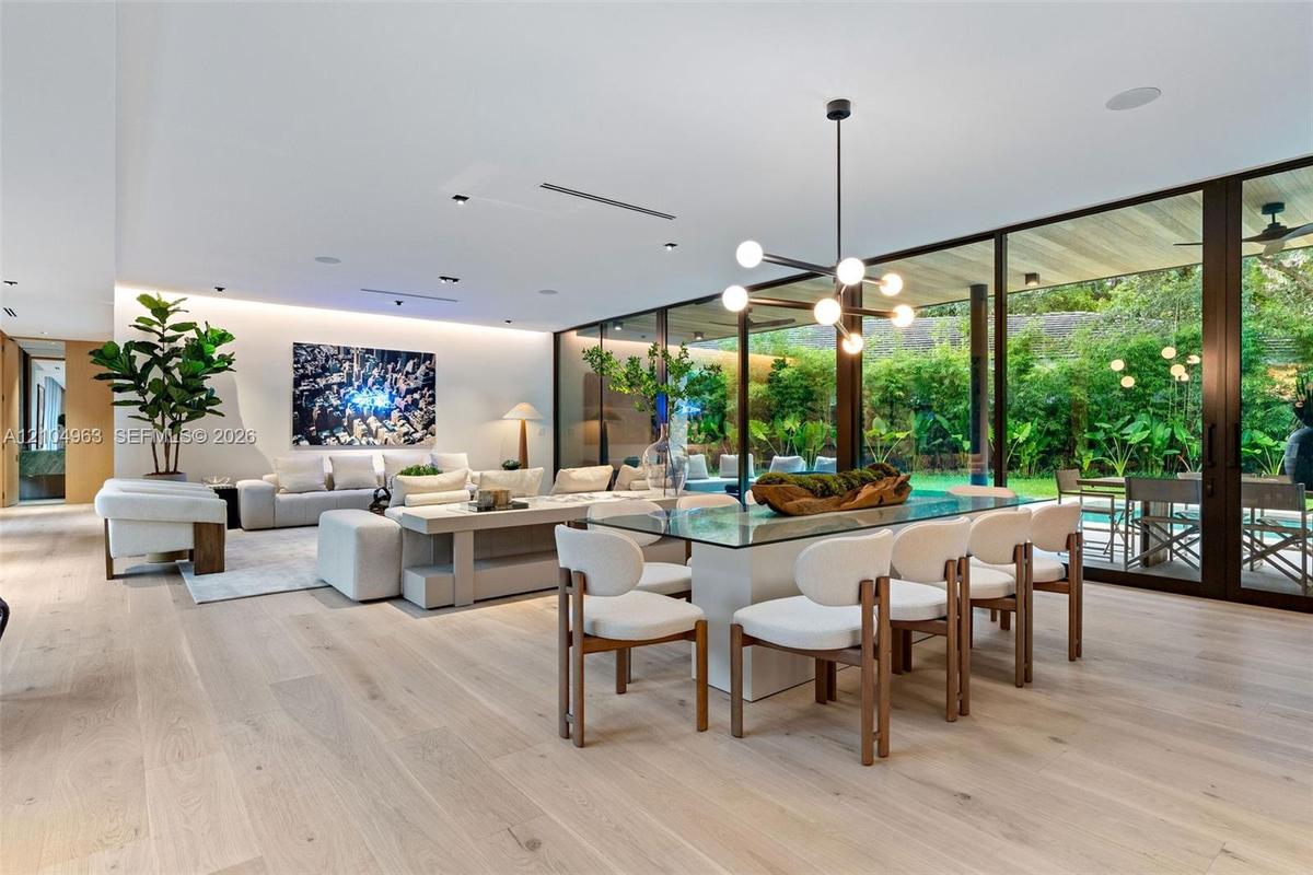 Open-concept interior featuring light wood-finish flooring, floor-to-ceiling glass panel walls, recessed architectural lighting, and a modern multi-ar