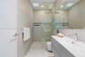 Modern bathroom featuring floor-to-ceiling textured wall tiling, a floating vanity with a seamless integrated sink, a glass-enclosed shower with a bui