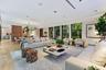 Open-concept living space featuring wood-finish flooring, floor-to-ceiling glass paneling, recessed ceiling lighting, and built-in audio speakers