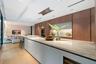 Kitchen featuring full-height wood-finish cabinetry, a lengthy stone-surfaced island, integrated double wall ovens, a built-in wine refrigerator, and 