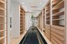 Custom storage cabinetry featuring light wood-finish shelving, integrated vertical LED lighting, a glass-topped center island, and recessed ceiling li