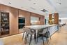 Kitchen featuring flat-panel wood cabinetry, integrated stainless steel double wall ovens, a stone-topped island with waterfall edge, and wood-finish 