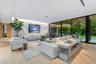 Floor-to-ceiling sliding glass walls, wood-finish flooring, recessed linear lighting, and integrated ceiling speakers