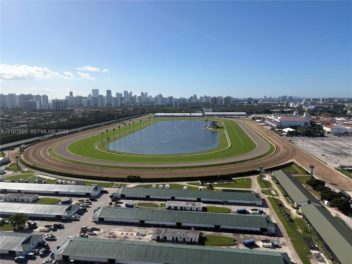 Aerial perspective of a large-scale track facility featuring a central grassed oval, an expansive interior water feature, a multi-lane dirt track, and