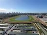 Aerial perspective of a large-scale track facility featuring a central grassed oval, an expansive interior water feature, a multi-lane dirt track, and