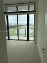 Floor-to-ceiling glass wall with sliding door access to a balcony, complemented by large-format neutral tile flooring