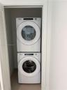 Stacked front-load washer and dryer unit enclosed within a dedicated laundry closet