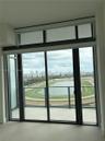 Floor-to-ceiling glass sliding doors with an upper transom window, balcony access, and railing overlooking a racetrack and cityscape