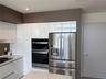 Glossy white cabinetry, built-in stainless steel double wall ovens, integrated stainless steel refrigerator, and recessed lighting