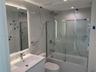 Bathroom featuring floor-to-ceiling large-format tile with decorative veining, vanity with an integrated basin, backlit wall mirror, and a tub-shower 