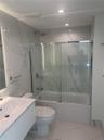Modern bathroom featuring full-height large-format stone-patterned wall tile, a floating vanity with an integrated basin, and a glass-enclosed shower 