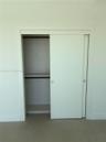 Minimalist closet featuring clean-lined sliding doors, integrated shelf, interior hanging rod, and recessed metal pulls