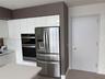 Kitchen featuring flat-panel white cabinetry, integrated stainless steel double wall ovens, a stainless steel French-door refrigerator, and solid-surf