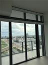 Floor-to-ceiling windows with black metal frames, integrated transom windows, and a private balcony featuring a glass panel railing