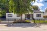 Single-story stucco exterior featuring a dark tile roof, horizontal slat metal fencing, and dark-framed windows