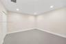 Neutral-toned room featuring large-format tile flooring, recessed ceiling lighting, and a dual-panel closet door