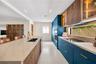 Modern kitchen featuring custom blue cabinetry, wood-finish lower cabinetry, stone-surface countertops, integrated under-cabinet lighting, and built-i