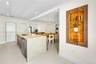 Kitchen island featuring a waterfall stone countertop, integrated stainless steel dishwasher, and a gooseneck faucet, accompanied by a recessed wall n