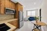 Kitchen featuring wood-finish cabinetry, stainless steel appliances, a solid-surface countertop, recessed ceiling lighting, and large-format tile floo