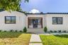 Stucco exterior featuring dark-trimmed windows, a flat tile roof, a wooden-framed entry, and a concrete paver walkway