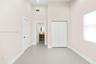 High-ceilinged room featuring neutral wall tones, large-format tile flooring, double-door closet cabinetry, and three-panel interior doors