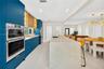 Kitchen featuring custom blue cabinetry, wood-finish shelving with integrated lighting, a waterfall-edge stone island, built-in stainless steel double