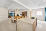 Kitchen island with waterfall countertop, wood-finish cabinetry, brass-toned faucet, recessed lighting, and decorative wood slat partition