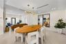 Open-concept interior featuring light-toned tile flooring, recessed linear lighting, a multi-arm brass finish chandelier, and large-scale floor-to-cei