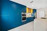 Kitchen featuring floor-to-ceiling blue cabinetry, built-in double wall ovens, wood-finish upper cabinets with integrated lighting, a stone-surfaced k
